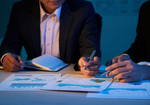 Close-up image of coworkers discussing financial charts at business meeting